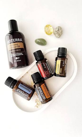 Olio di cocco frazionato dōTERRA con flaconi di Peppermint, Wild Orange e Lemon su un vassoio bianco
