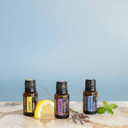Flaconi dōTERRA Lemon, Lavender e Peppermint su marmo con limone, lavanda e basilico freschi